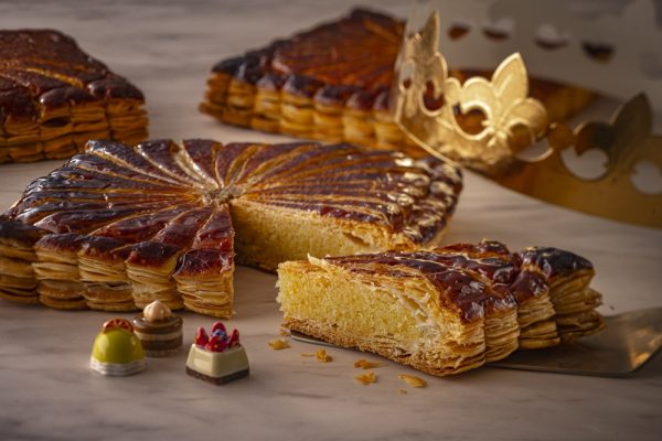新年の幸運を呼ぶフランス菓子　ペストリーシェフ佐藤 浩一就任後 初の「ガレットデロワ」が登場　ユニークなスクエア型＆スイーツモチーフ全10種からランダム1種のフェーヴ付き 2026年1月1日（木）より ペストリーショップ「ドーレ」にて販売開始 横浜ベイシェラトン ホテル＆タワーズ 2025年12月5日 14時03分 2 新たな年のスタートに家族や友人と楽しめる　スクエア型のガレットデロワ 横浜ベイシェラトン ホテル＆タワーズでは、ペストリーショップ「ドーレ」（B1F）にて、フランス伝統の祝菓子「ガレットデロワ」を2026年1月1日（木）から1月31日（土）までの期間限定でご提供いたします。 “幸運を呼ぶお菓子”としてフランスの新年に欠かせない「ガレットデロワ」は、“王様の菓子”という名の通り、家族やご友人が集う特別なひとときを華やかに演出いたします。パイの中には“フェーヴ”と呼ばれる小さな陶製のチャームが一つだけ隠されており、当たった方には1年間の幸福が訪れると言い伝えられています。王冠をかぶり、皆で幸運を祝福するのもこの伝統的なお菓子の魅力です。 本年は、2025年8月に就任したペストリーシェフ 佐藤 浩一が手掛ける、“初”のガレットデロワをご用意しました。フランスにて長年研鑽を重ねた佐藤シェフは、あえて伝統的な丸型にこだわらずユニークな“スクエア型” にアレンジ。切り分けやすく、テーブルを華やかに彩るモダンなスタイルに仕立てています。バターをたっぷりと使用したサクサクと香ばしいパイ生地に、濃厚なカスタードを合わせた上品な甘さのアーモンドクリームを重ねた、豊かな風味が広がる逸品です。アーモンドのコクと贅沢な口当たりが調和し、シンプルでありながら奥行きのある味わいをお楽しみいただけます。また、本場の伝統を受け継ぎ、ケーキの中にはフェーヴに見立てたアーモンドをひと粒忍ばせています。陶製のフェーヴは安全面への配慮から別添えでご用意し、全10種類のスイーツモチーフの中からランダムで1種をお渡しいたします。コレクションとしても楽しい可愛らしいデザインで、新年の特別な思い出としてお持ち帰りいただけます。 　新年の幕開けに、ご家族や親しい友人とのお集まりに、ペストリーショップ「ドーレ」の「ガレットデロワ」で心華やぐひとときをお過ごしください。